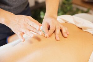 Home page From above of crop anonymous man applying needles on back of client during acupuncture procedure